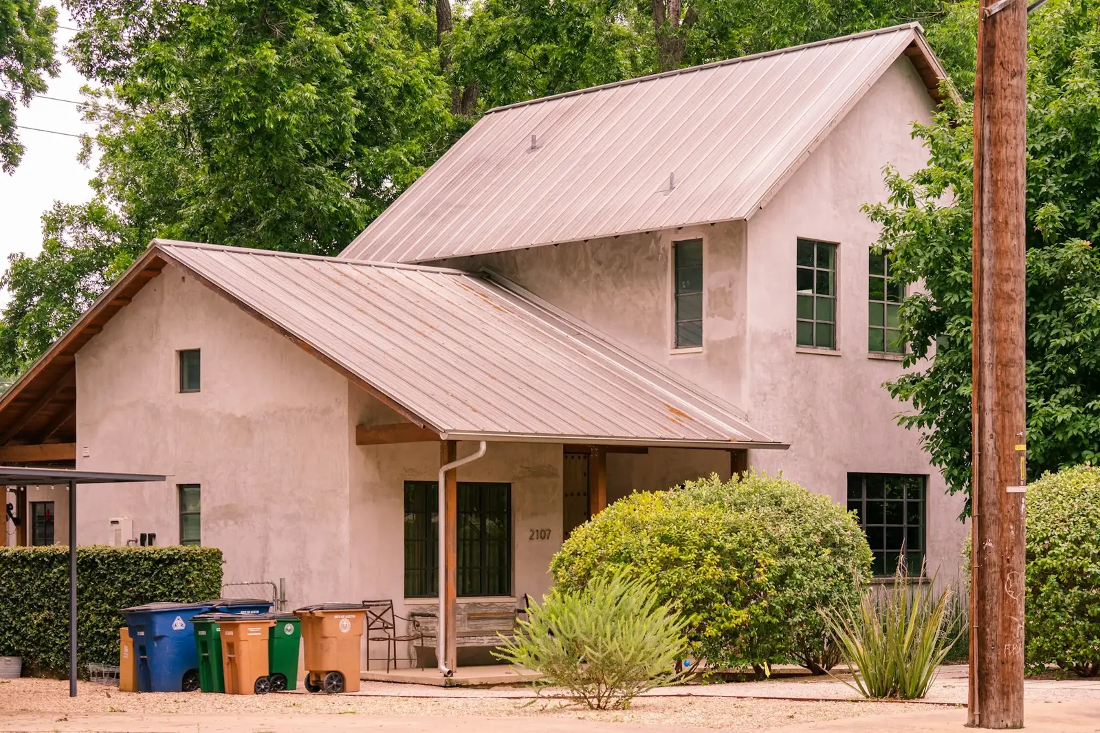 A restrained stucco house beneath mature trees in Austin