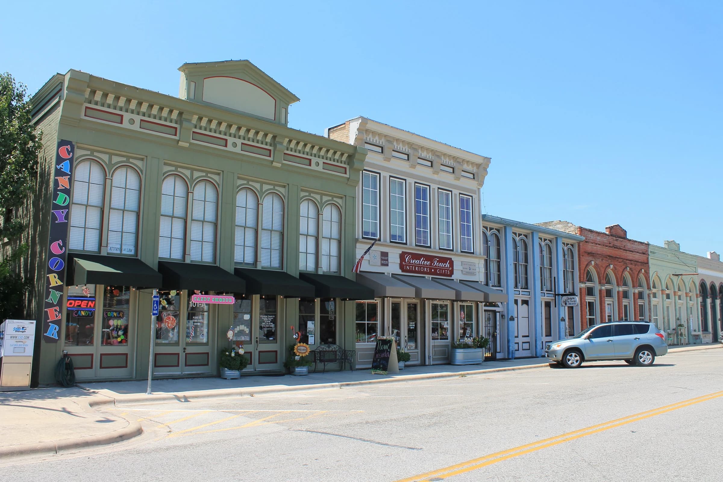 Historic brick storefronts painted sage, cream and blue in the Hutto Commercial Historic District in Hutto, Texas