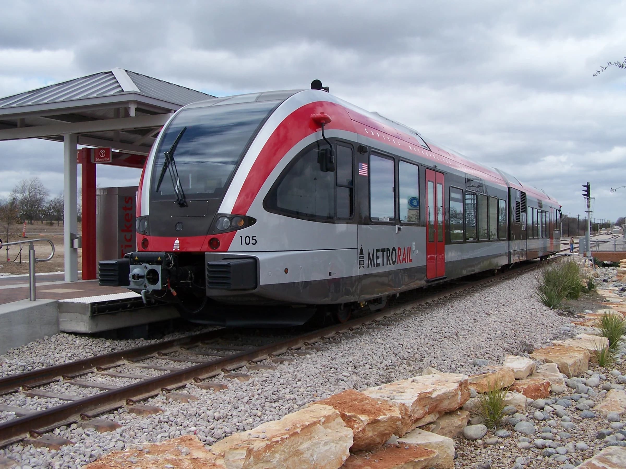 A red and silver Capital Metro MetroRail train waiting at the Leander station platform, the northern end of the Red Line commuter rail to downtown Austin
