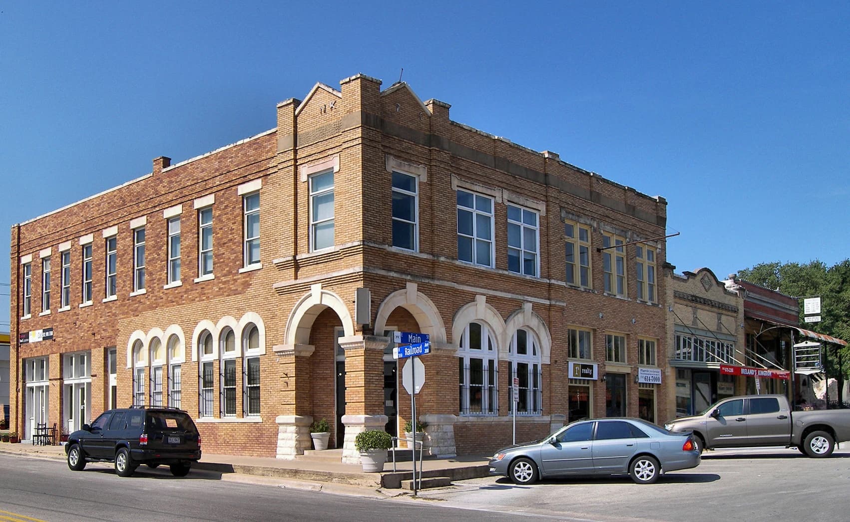 A two-story brick building with arched windows at the corner of Main and Railroad streets in the East Main Street Historic District of Pflugerville, Texas